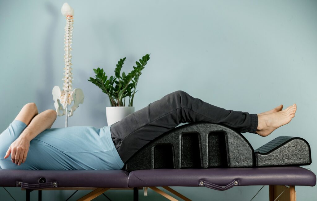 A man lying on the pilates arc in constructive rest postion, si joint pain relief