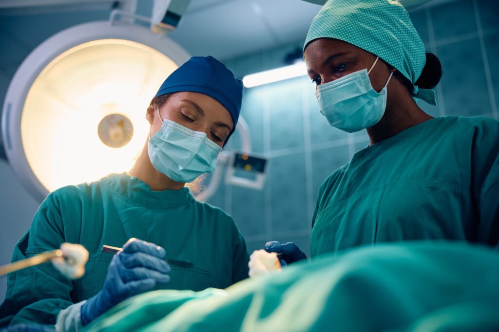 Female doctors performing surgical procedure on a patient in operating room.