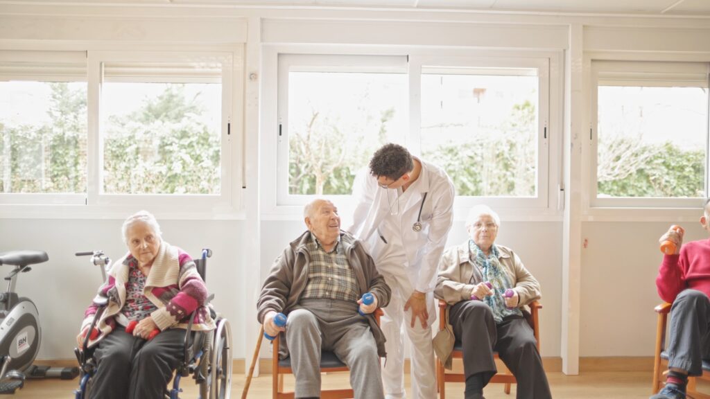 Group of seniors engaging in physical therapy in a sunlit exercise room.