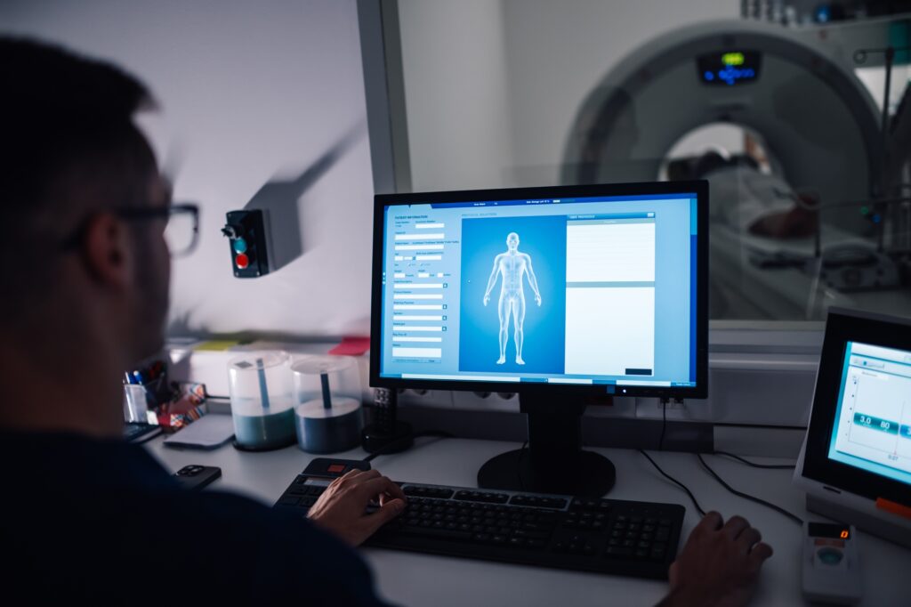 Radiology technician working at a computer screen during CT scan.